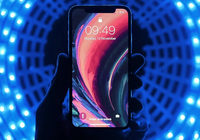 A hand holding a smartphone with its lock screen visible.