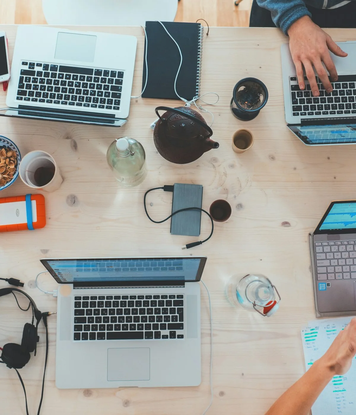 Laptops, notebooks, and phones on a shared working table.